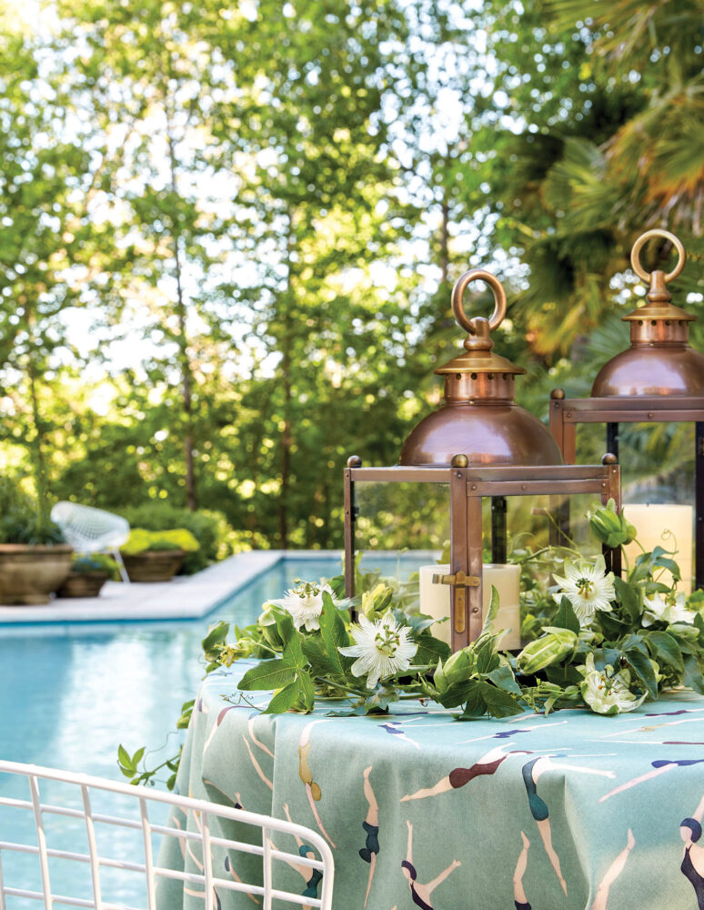 Two copper Bevolo lanterns on an outdoor table by a pool.