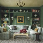 Adjacent to the primary bedroom, this sitting area is cocooned in ‘Boxwood’ by Dunn-Edwards. Bookshelves display the owners’ collection of ironstone. An early Victorian painting hangs above a sofa upholstered in a floral from Meredith Ellis Textiles.