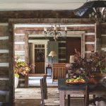 A view from the dining area through the entry into the living room is bathed in soft light and punctuated with fall leaves and greenery in rustic containers.