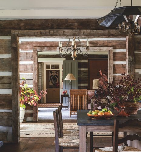 A view from the dining area through the entry into the living room is bathed in soft light and punctuated with fall leaves and greenery in rustic containers.