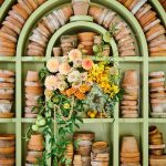 A display of terra-cotta pots with arrangement of dahlias, roses, orchids, and celosia.