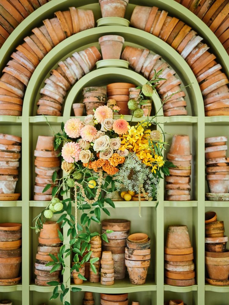 A display of terra-cotta pots with arrangement of dahlias, roses, orchids, and celosia.