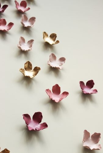 pink and gold ceramic flowers hang on a wall
